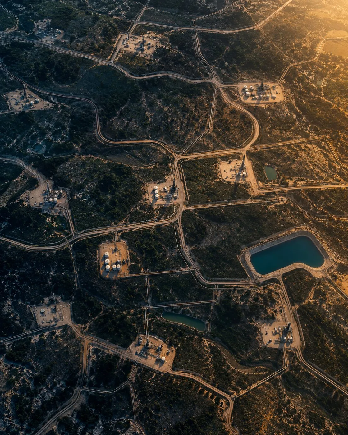 Aerial view of well pads and access roads across open desert